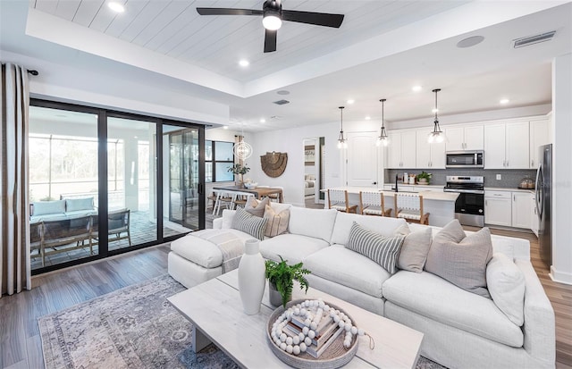 living room with ceiling fan, sink, dark hardwood / wood-style flooring, a tray ceiling, and wood ceiling