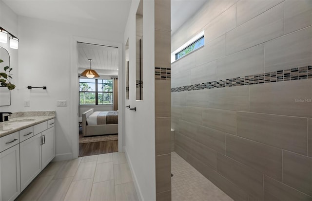 bathroom featuring tiled shower, hardwood / wood-style floors, vanity, and a healthy amount of sunlight