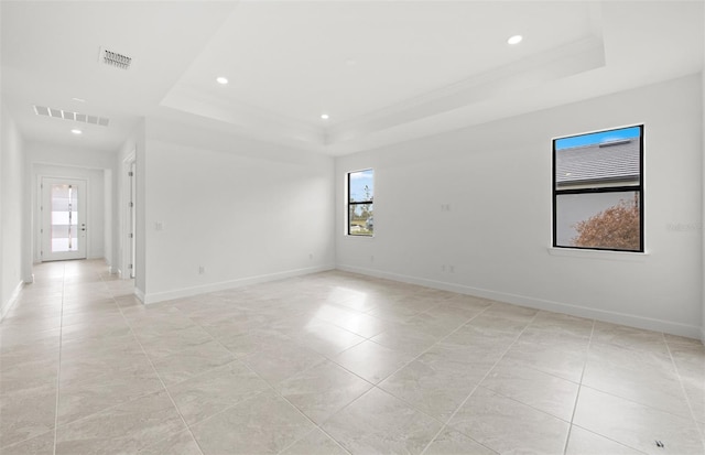 empty room featuring a raised ceiling and crown molding