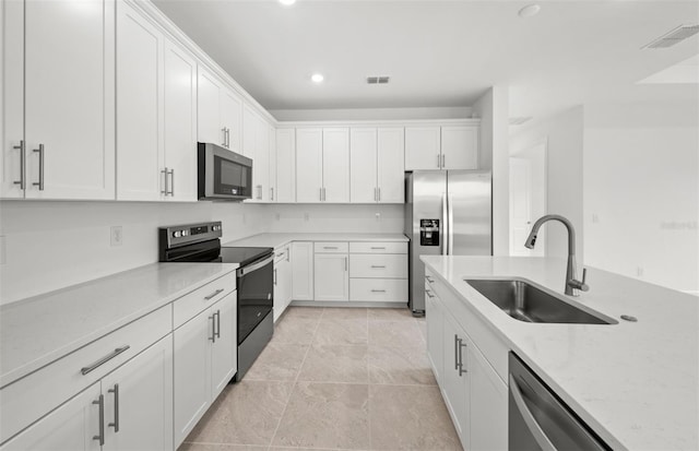 kitchen featuring white cabinetry, appliances with stainless steel finishes, sink, and light stone counters