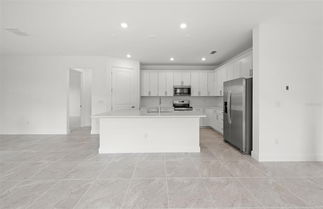 kitchen with stainless steel appliances, an island with sink, and white cabinets