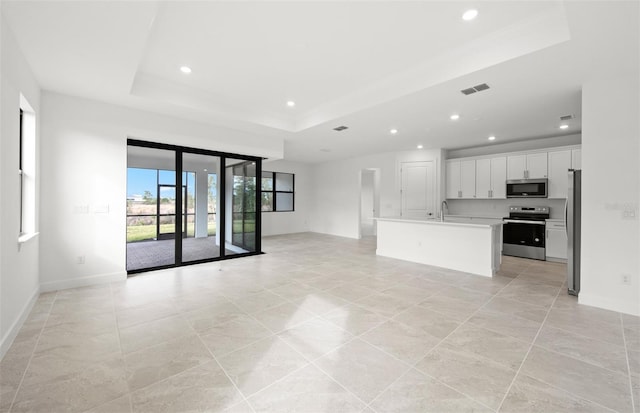 unfurnished living room featuring sink and a tray ceiling