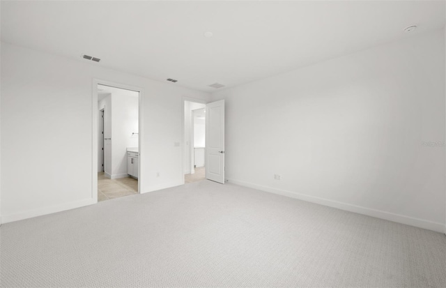 unfurnished bedroom with light carpet and ensuite bathroom