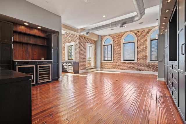 405 Central Ave Unit 700, Saint Petersburg, FL 33701 - unfurnished living room featuring brick wall, wine cooler, wood finished floors, and baseboards