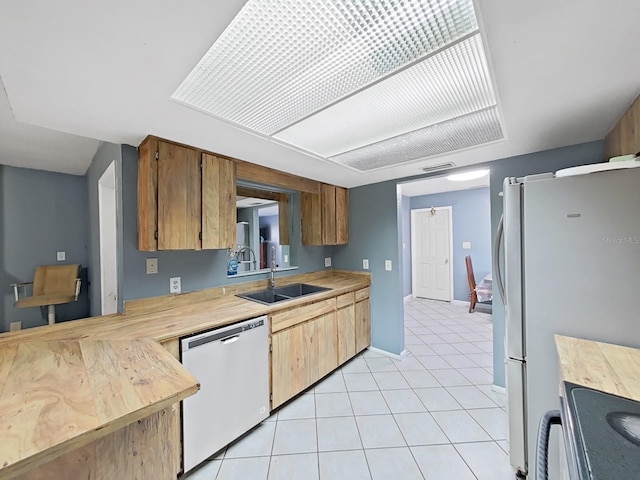 kitchen featuring sink, light tile patterned floors, and white appliances