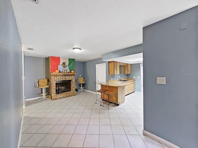 kitchen with a kitchen breakfast bar, sink, a fireplace, a textured ceiling, and butcher block countertops