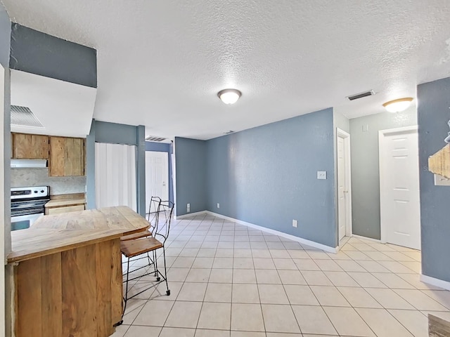 kitchen with range with electric stovetop, kitchen peninsula, a textured ceiling, and a kitchen breakfast bar