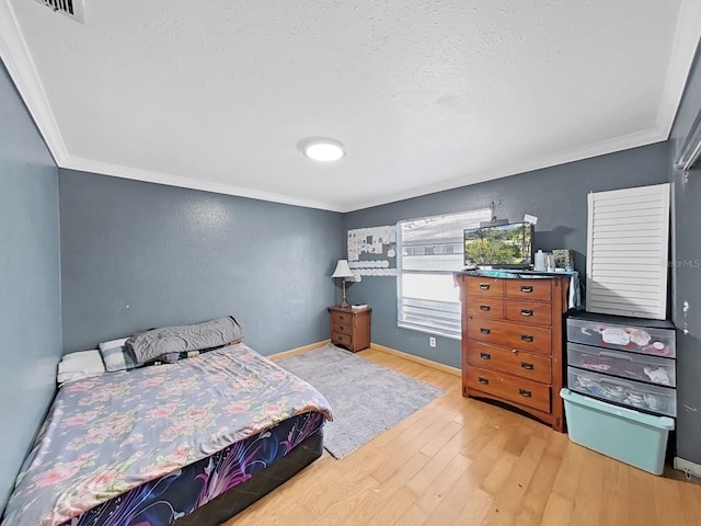 bedroom with a textured ceiling, hardwood / wood-style flooring, and ornamental molding