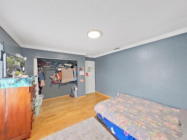 bedroom featuring hardwood / wood-style floors, a closet, and crown molding