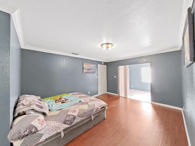 bedroom featuring a textured ceiling, wood-type flooring, and ornamental molding