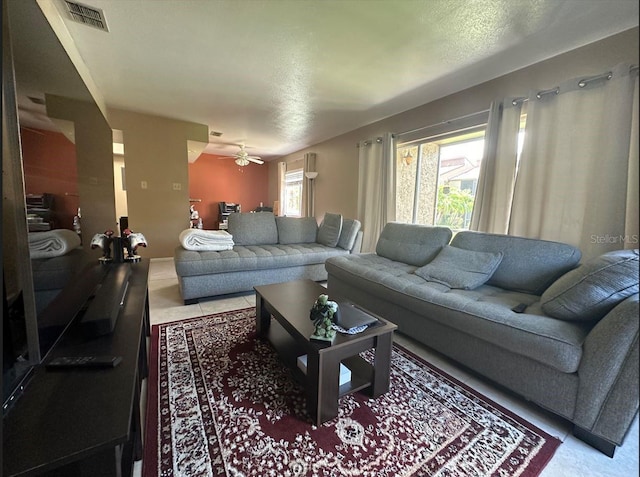 living room with a textured ceiling, plenty of natural light, and ceiling fan