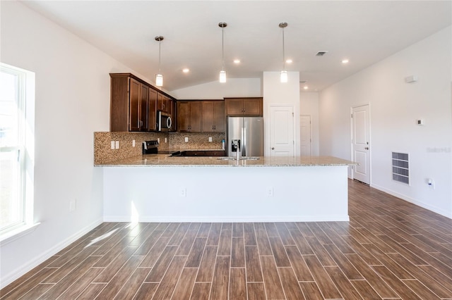 kitchen with lofted ceiling, dark hardwood / wood-style floors, light stone countertops, decorative light fixtures, and stainless steel appliances