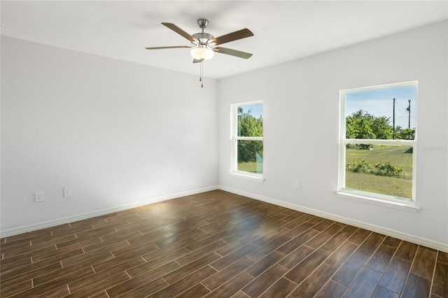 empty room featuring a wealth of natural light, ceiling fan, and dark wood-type flooring