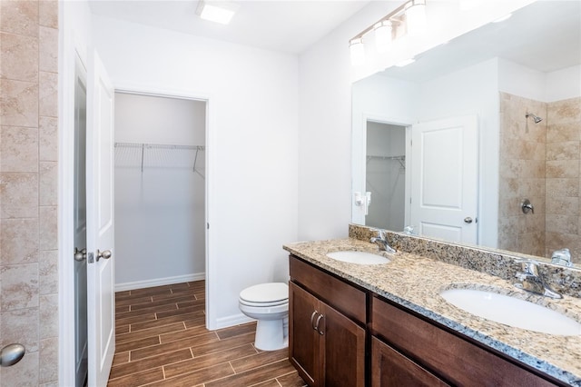 bathroom featuring toilet, a tile shower, and vanity