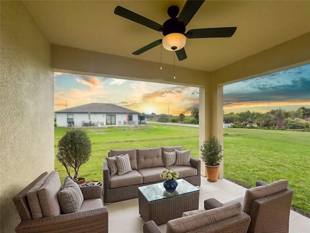 patio terrace at dusk with ceiling fan, an outdoor hangout area, and a yard