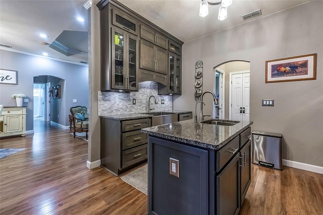 kitchen with a center island with sink, dark hardwood / wood-style flooring, sink, and dark stone counters