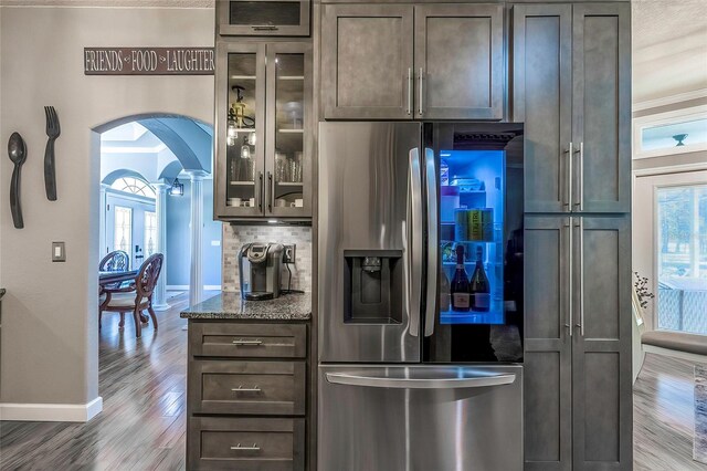 kitchen with hardwood / wood-style floors, stainless steel fridge, dark stone counters, and a healthy amount of sunlight