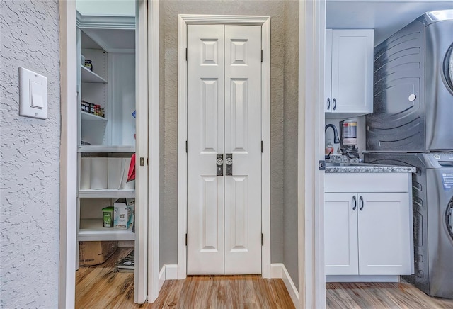 interior space featuring cabinets, light hardwood / wood-style flooring, and stacked washer and clothes dryer