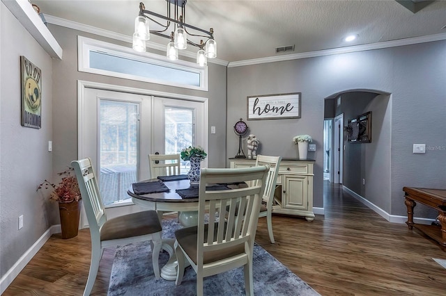 dining space with french doors, dark hardwood / wood-style flooring, a notable chandelier, crown molding, and a textured ceiling