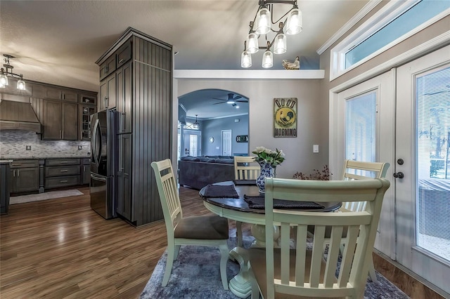 dining room with ceiling fan with notable chandelier, ornamental molding, and dark wood-type flooring