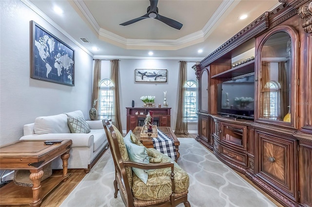 sitting room with light wood-type flooring, plenty of natural light, ornamental molding, and ceiling fan