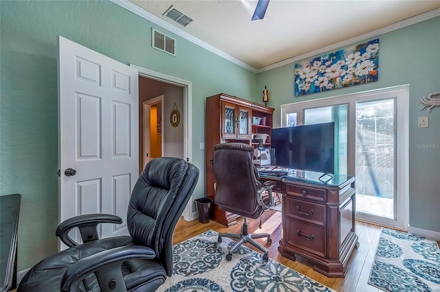 home office featuring light hardwood / wood-style floors, a wealth of natural light, and crown molding