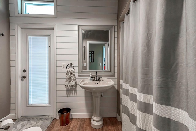 bathroom featuring hardwood / wood-style flooring and wooden walls