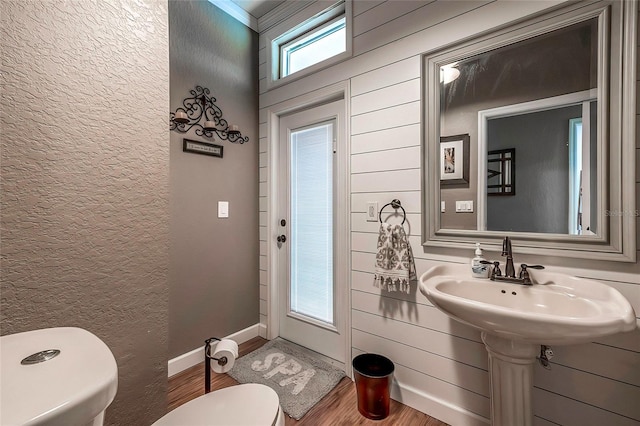 bathroom with wooden walls, hardwood / wood-style floors, and toilet