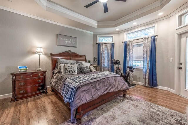 bedroom featuring a tray ceiling, ceiling fan, crown molding, and wood-type flooring