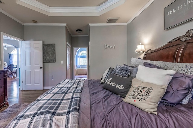 bedroom featuring dark wood-type flooring, a tray ceiling, and ornamental molding