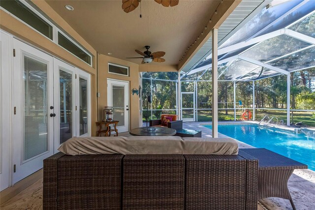 view of pool featuring outdoor lounge area, ceiling fan, a patio area, and a lanai