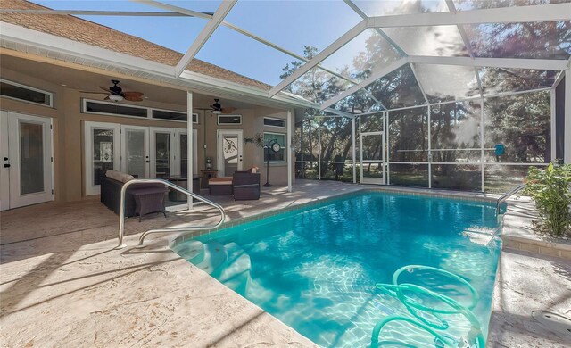 view of pool with glass enclosure, ceiling fan, french doors, pool water feature, and a patio