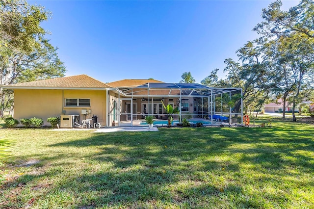 back of house with glass enclosure, a patio area, and a lawn