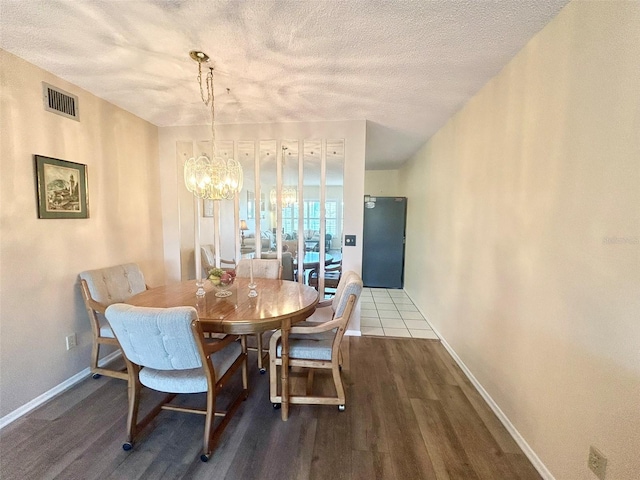 dining area featuring hardwood / wood-style flooring, a textured ceiling, and an inviting chandelier