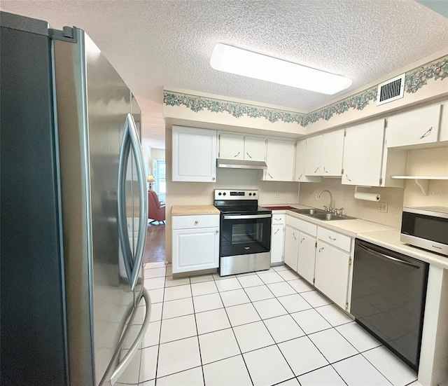 kitchen featuring appliances with stainless steel finishes, a textured ceiling, white cabinetry, and sink