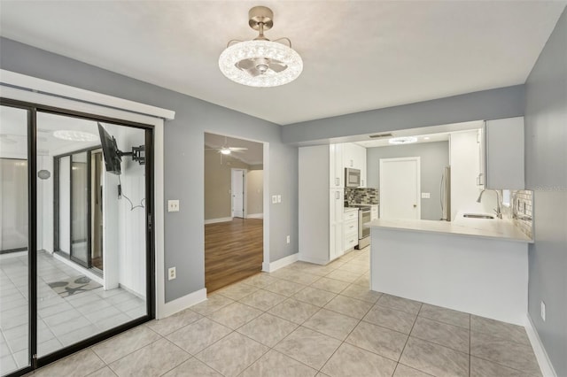 kitchen with white cabinetry, sink, stainless steel appliances, backsplash, and light tile patterned floors