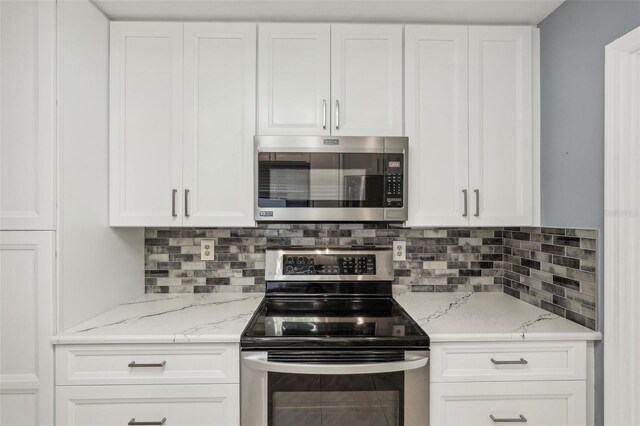 kitchen featuring backsplash, light stone counters, white cabinets, and appliances with stainless steel finishes