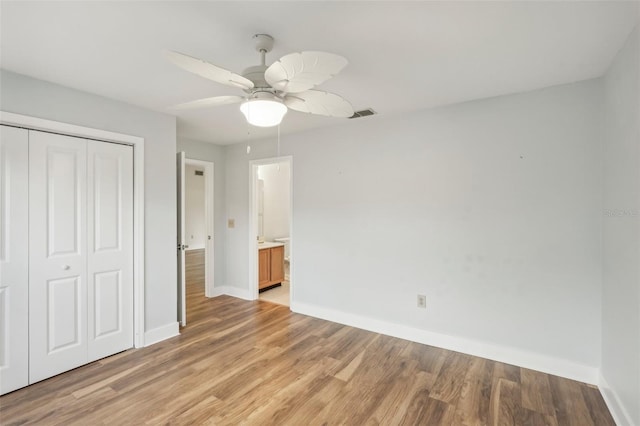 unfurnished bedroom with ensuite bath, ceiling fan, a closet, and light wood-type flooring