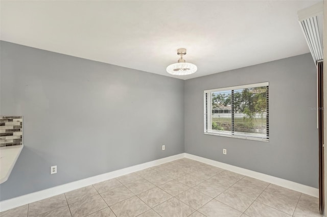 tiled spare room with a chandelier