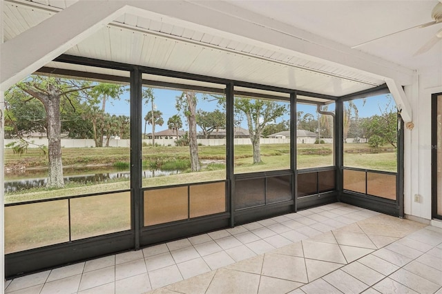 unfurnished sunroom featuring beam ceiling, ceiling fan, and a water view