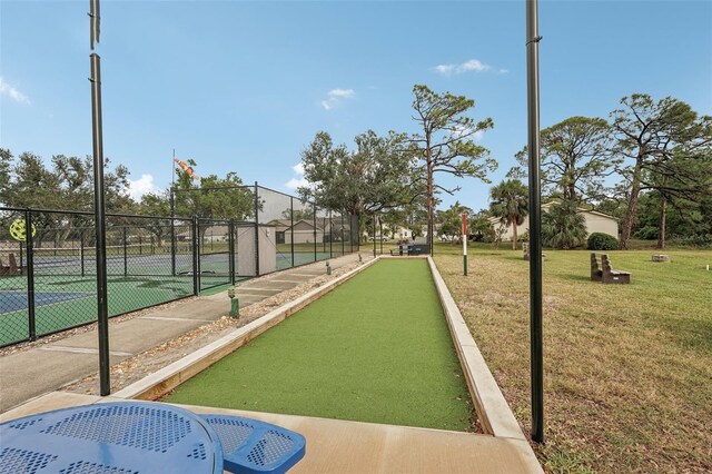 view of home's community with a lawn and tennis court