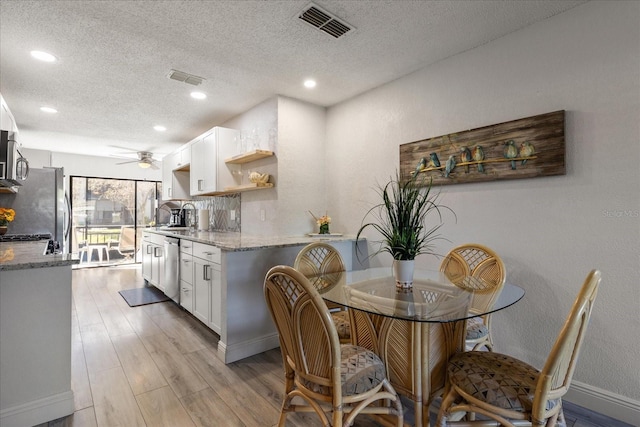 kitchen featuring light stone countertops, white cabinets, a textured ceiling, and appliances with stainless steel finishes