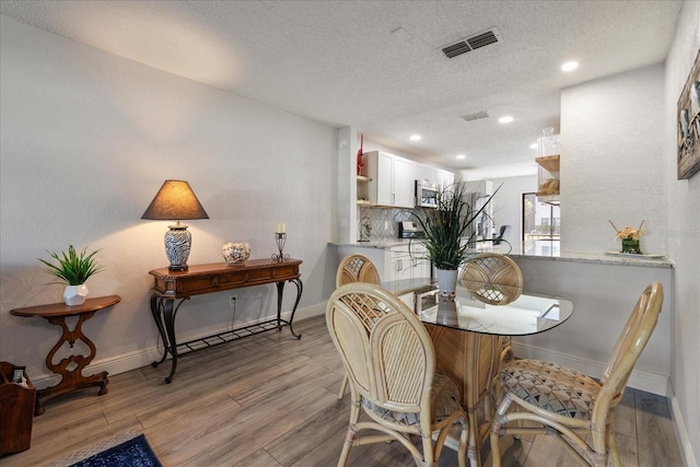 dining area featuring light wood-type flooring and a textured ceiling