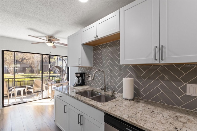 kitchen with backsplash, white cabinets, sink, a textured ceiling, and light stone counters