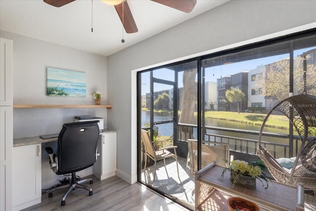 home office featuring ceiling fan, light hardwood / wood-style flooring, and a water view