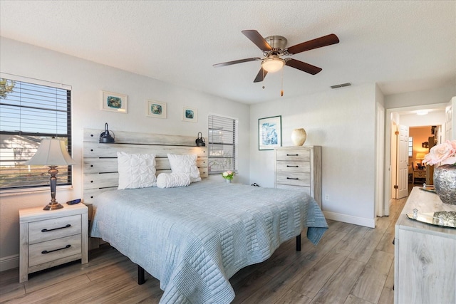 bedroom with ceiling fan, a textured ceiling, and light hardwood / wood-style flooring