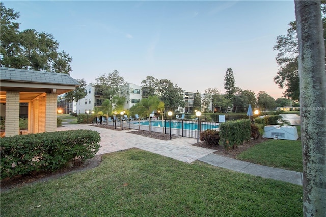 pool at dusk featuring a patio area and a yard