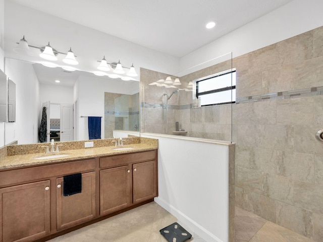 bathroom featuring tile patterned flooring, a tile shower, and vanity