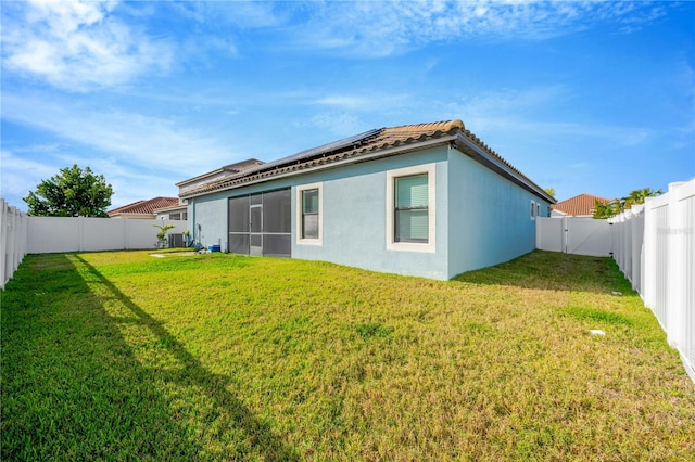 back of property with a lawn and solar panels