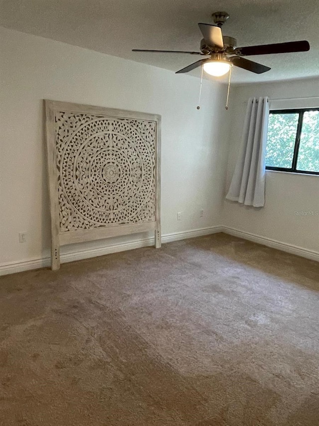 carpeted spare room featuring ceiling fan and a textured ceiling